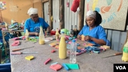 Florence Auma, right, uses components of discarded flip-flops to create coasters, at Ocean Sole, in Karen, Kenya, Jan. 17, 2024. (Mariama Diallo/VOA)