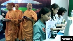 FILE - Thai Buddhist Monks walk past a line of internet users at an internet expo on May 25, 2000. (REUTERS/File photo)