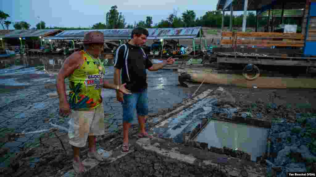 Unable to draw water from the Puraquequara River, fishermen dig a hole in the mud to access water for bathing and washing dishes, in Manaus, Oct. 3, 2023.