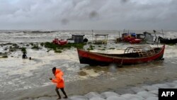 A man pulls a fishing boat to shore as a preventive measure during rainfall in Kuakata, Bangladesh, on May 26, 2024, ahead of cyclone Remal's landfall.