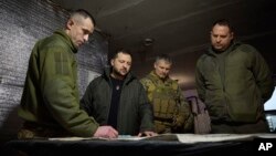 In this photo provided by the Ukrainian Presidential Press Office, President Volodymyr Zelenskyy, 2nd left, looks at a map during a visit to Avdiivka, the site of fierce battles with Russian troops, in Ukraine's Donetsk region, Dec. 29, 2023.