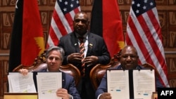 US Sec. of State Antony Blinken (L) and Papua New Guinea's Defense Minister Win Bakri Daki (R) show documents after signing a security agreement as Papua New Guinea's Prime Minister James Marape (C) looks on in Port Moresby on May 22, 2023. 