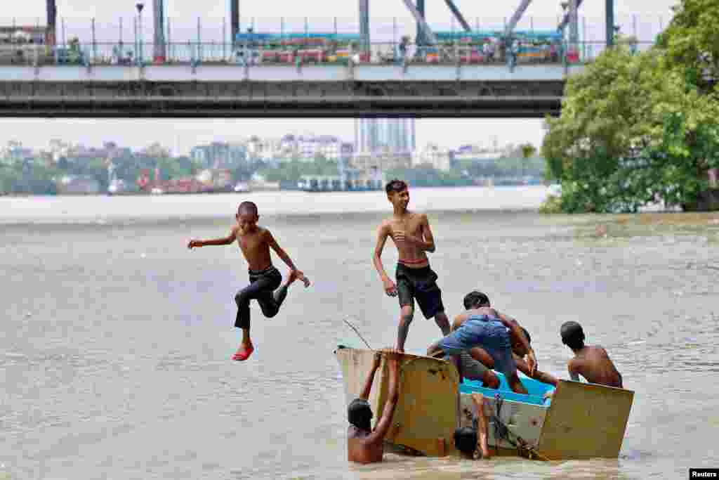 Seorang anak laki-laki melompat dari perahu ke sungai Gangga untuk menyengarkan tubuhnya di tengah terik musim panas di Kolkata, India, 8 Mei 2024. (REUTERS/Sahiba Chawdhary)