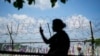 A visitor takes a photo near a wire fence decorated with ribbons with messages wishing for the reunification of the two Koreas at the Imjingak Pavilion in Paju, South Korea, June 26, 2024. 