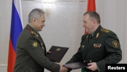 세르게이 쇼이구 러시아 국방부 장관(왼편)과 빅토르 흐레닌 벨라루스 국방부 장관(오른편)이 25일 벨라루스 민스크에서 러시아 전술핵무기 배치 협정에 서명한 뒤 협정문을 교환하며 악수하고 있다. (자료사진)