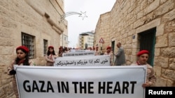 Sejumlah anak-anak pramuka memegang spanduk bertuliskan solidaritas terhadap warga Palestina di Gaza, dalam sebuah acara di Kota Tua Bethlehem, Tepi Barat, pada 24 Desember 2023. (Foto: Reuters/Mussa Issa Qawasma)