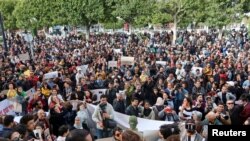 FILE - Members of rights groups carry banners during a protest, after Tunisian President Kais Saied ordered security forces to stop all illegal migration and expel all undocumented migrants, in Tunis, Tunisia, Feb. 25, 2023.