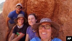 In this undated photo provided to the Associated Press by Stellenbosch University, researcher Michele Francis, right, and other researchers pose next to an ancient termite mound in Namaqualand, South Africa. 