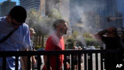 People cool off in misters along the Las Vegas Strip, July 7, 2024, in Las Vegas. 