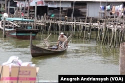 Seorang pria terlihat sedang mengemudikan sampan di Kampung Nelayan Seberang, Kecamatan Medan Belawan, Kota Medan, Sumatra Utara. (VOA/Anugrah Andriansyah)