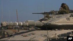 An Israeli soldier sits atop a tank in a staging area near the Gaza border in southern Israel, May 24, 2024. 