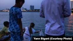 ស្រ្តីម្នាក់ព្រលែងត្រី ដែលជាសត្វគេនិយមព្រលែងដូចសត្វចាបនិងសត្វដទៃទៀត ចូលទៅក្នុងចំណុចប្រសព្វគ្នារវាងទន្លេសាប និងទន្លេមេគង្គ នៅថ្ងៃវិសាខបូជា។ (រូបផ្តល់ឱ្យដោយលោក Yann Bigant)