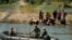 Penjaga mendorong para migran yang menunggu di gundukan pasir di tengah sungai Rio Grande untuk berbalik ketika mereka mencoba menyeberangi sungai tersebut dari Meksiko ke AS, Sabtu, 23 September 2023. (AP/Eric Gay)