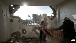 Warga Palestina mengumpulkan barang-barang mereka dari rumah mereka yang rusak pasca serangan udara Israel di Rafah, Jalur Gaza selatan, 27 Januari 2024. (Foto: AP)