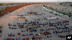 Migran menunggu di luar gerbang pagar perbatasan menuju El Paso, Texas, untuk diproses oleh Patroli Perbatasan, Kamis, 11 Mei 2023. (AP/Andres Leighton)