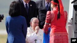 Pope Francis picks up a piece of aaruul or Mongolian curd cheese as he arrives at Ulaanbaatar's international airport Chinggis Khaan, Sept. 1, 2023. 
