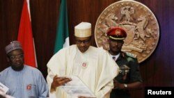 Nigeria's President Muhammadu Buhari looks at a sample of the new N1,OOO note