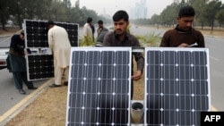 资料照片：2014年2月2日巴基斯坦工人在伊斯兰堡的道路分隔线上准备太阳能灯板。