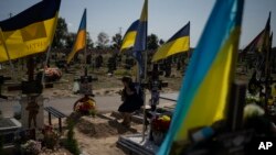 A woman cries at the grave of her son, who died fighting in the war, as Ukrainians mark Independence Day in Kharkiv, Ukraine, Aug. 24, 2023. 