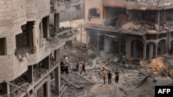 9일 가자지구 난민촌 인근 지역에서 이스라엘 공습에 파괴된 시설들을 팔레스타인인들이 살펴보고 있다.