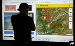 ชาวเมืองรูอิโดโซ รัฐนิวเม็กซิโก ยืนดูแผนที่ที่แสดงให้เห็นบริเวณที่เกิดไฟป่า ขณะหลบภัยอยู่ที่ศูนย์บรรเทาทุกข์ในเมืองรอสเวลล์ เมื่อ 18 มิ.ย. 2567