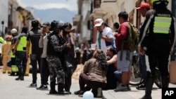 Police talk to people next to the site where a car was crushed by debris after an earthquake shook Cuenca, Ecuador, March 18, 2023.