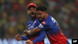 Royal Challengers Bengaluru's Virat Kohli, left, and Mohammed Siraj celebrate the dismissal of Chennai Super Kings' Daryl Mitchell during a cricket match between Royal Challengers Bengaluru and Chennai Super Kings in Bengaluru, India, May 18 , 2024. 