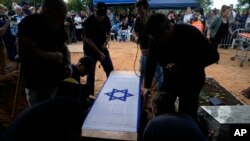 The coffin containing the remains of Alon Shamriz, 26, is lowered to his grave in the cemetery of Kibbutz Shefayim, Israel, Dec. 17, 2023. Shamriz was one of three hostages mistakenly shot to death by Israeli troops in Gaza City on Dec. 15, 2023.