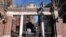 FILE - A passer-by walks through a gate to the Harvard University campus, in Cambridge, Massachusetts, Jan. 2, 2024. 