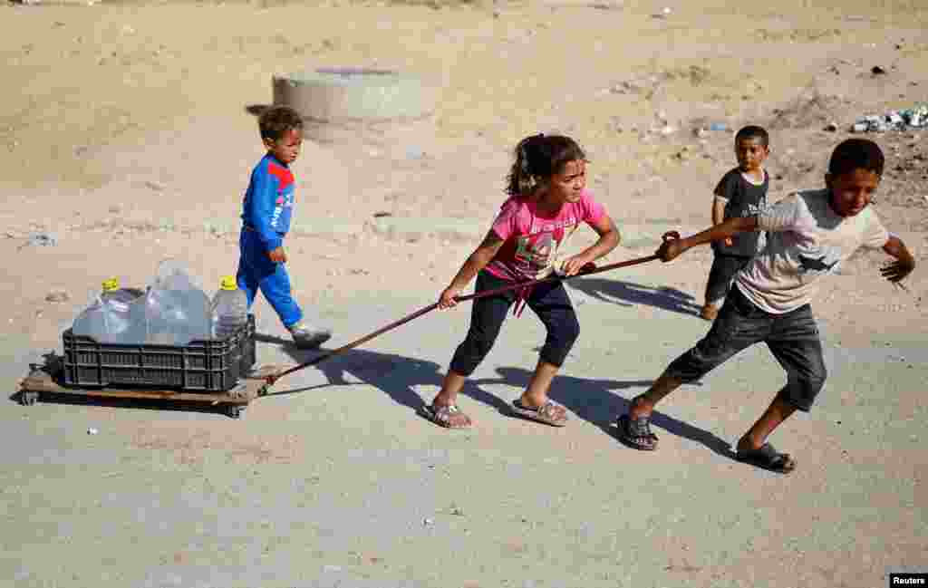 Anak-anak Palestina menarik wadah air mereka saat mengungsi dari Rafah, ketika pasukan Israel melancarkan operasi darat dan udara di bagian timur kota Gaza selatan, di Jalur Gaza selatan.