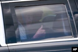 Former U.S. President Donald Trump gives a thumbs-up as he sits in the rear of his limousine departing Trump International Golf Club in West Palm Beach, Florida, April 2, 2023.