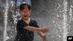 A girl reacts as she plays in a fountain at a shopping mall in Beijing, June 23, 2023. 