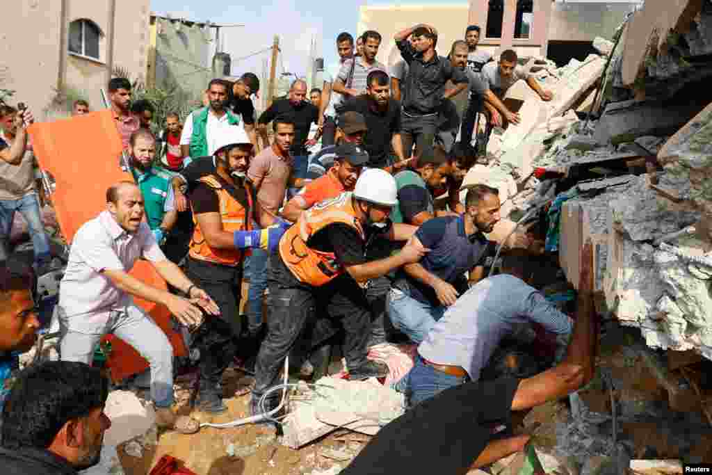 Palestinians search for casualties under the rubble of a house destroyed in Israeli strikes in Khan Younis, in the southern Gaza Strip, Oct. 8, 2023. 