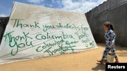 2일 가자지구 남부 라파에 팔레스타인 난민 어린이가 텐트 옆을 지나고 있다. 텐트에는 친팔레스타인 시위를 하는 대학생들과의 유대 메시지가 쓰여있다.