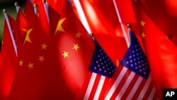 FILE - The flags of China and the U.S. are displayed on top of a trishaw in Beijing, Sept. 16, 2018. 