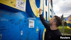 Ukraine President Volodymyr Zelenskiy signs a road sign in Donetsk region, Ukraine, April 19, 2024. (Ukrainian Presidential Press Service/Handout via Reuters)