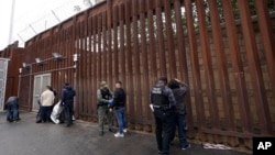FILE - Federal officers remove handcuffs from men before releasing them through a gate in a border wall to Tijuana, Mexico, March 15, 2023, in San Diego. 