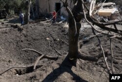 Penduduk setempat berdiri di samping rumah tempat tinggal yang hancur akibat serangan rudal di wilayah Kyiv, pada 27 Agustus 2023. (Foto: AFP)