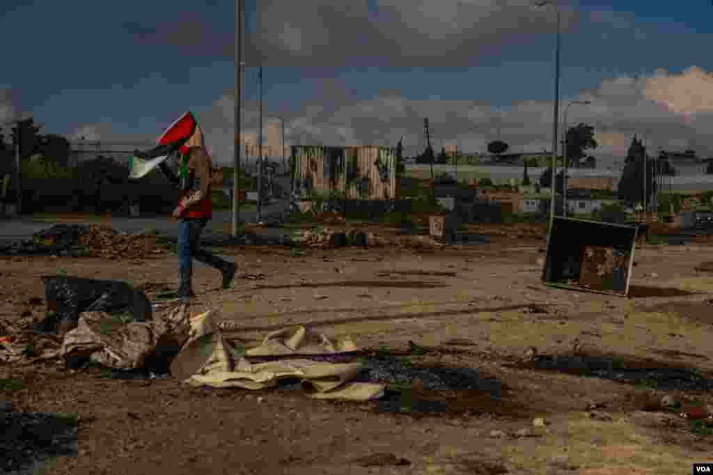A Palestinian boy holds a Palestinian flag during protests against Israeli soldiers on the outskirts of Ramallah, in the West Bank, Oct. 18, 2023. (Yan Boechat/VOA)
