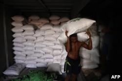 iLUSTRASI - Seorang buruh menurunkan karung beras dari kapal di sepanjang dermaga di Yangon, 28 Juni 2023. (Sai Aung MAIN / AFP)