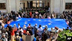 Protesters with a giant EU flag gather outside the parliament building in Tbilisi, Georgia, April 15, 2024, to protest against the "the Russian law" as it is similar to a law that Russia uses to stigmatize independent news media and organizations. 