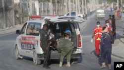 FILE - Security carry away victims injured during fighting between al-Shabab extremists and soldiers in Mogadishu, Somalia, Feb. 21, 2023.