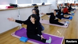Seorang instruktur melatih para lansia gerakan yoga dalam kelas yoga di Mama Sunset, sebuah pusat pelatihan untuk para lansia di China, di Beijing, pada 15 Januari 2024. (Foto: Reuters/Tingshu Wang)