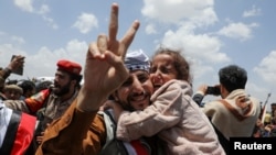 A freed prisoner gestures while holding a child after arriving at Sanaa Airport on an International Committee of the Red Cross (ICRC)-chartered plane, amid a prisoner swap between two sides in the Yemen conflict, in Sanaa, Yemen.