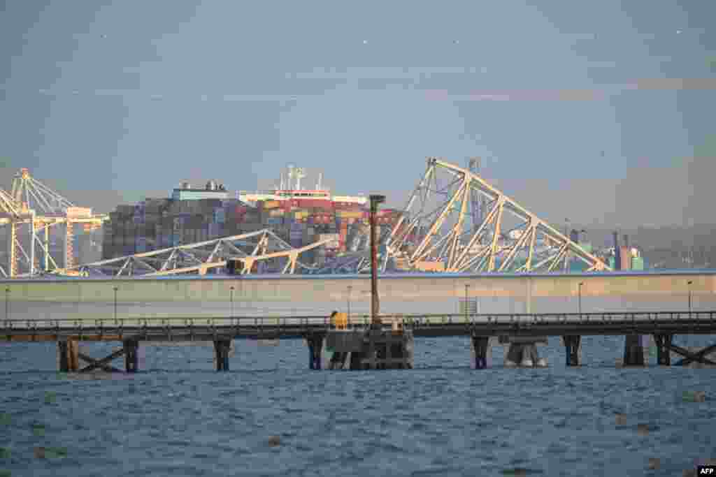 The steel frame of the Francis Scott Key Bridge sits on top of a container ship after it struck the bridge in Baltimore, March 26, 2024.&nbsp;The collapse sent multiple vehicles and up to 20 people plunging into the harbor below.&nbsp;