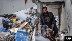 A man salvages food packages from a building that was hit overnight during Israeli bombardment in Rafah in the southern Gaza Strip, March 26, 2024.