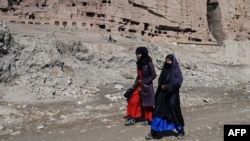 Sejumlah perempuan Afghanistan berjalan dekan patung Buddha Bamiyan yang dihancurkan Taliban pada 2001 di Provinsi Bamiyan, Afghanistan, 7 Maret 2024. Penembakan terhadap turis asing terjadi di wilayah tersebut pada Jumat, 17 Mei 2024. (Foto: Wakil kohsar / AFP)