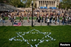 29일 팔레스타인을 지지하는 행렬이 컬럼비아 대학교 캠퍼스 잔디에 꽂힌 이스라엘을 의미하는 다비드 깃발 장식 옆을 지나고 있다.