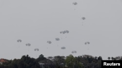 Humanitarian aid falls through the sky towards the Gaza Strip after being dropped from an aircraft, amid the ongoing conflict between Israel and the Palestinian Islamist group Hamas, as seen from Israel, April 25, 2024. 