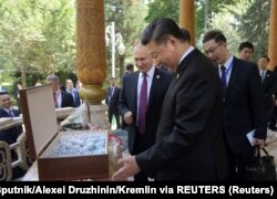 Presiden Rusia Vladimir Putin menghadiahkan es krim kepada Presiden China Xi Jinping sambil mengucapkan selamat ulang tahun di Dushanbe, Tajikistan, 15 Juni 2019. (Foto: via REUTERS)